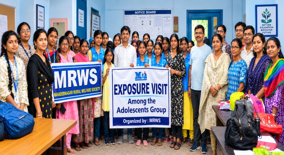 A large group of students and organizers holding banners for an exposure visit by the Mahadebnagar Rural Welfare Society indoors.