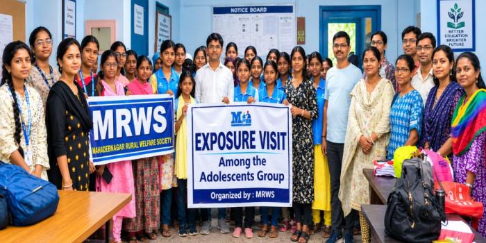 A large group of students and organizers holding banners for an exposure visit by the Mahadebnagar Rural Welfare Society indoors.